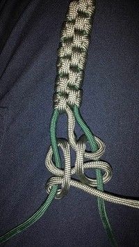 a green and white rope on top of a blue shirt with an attached knot in the middle