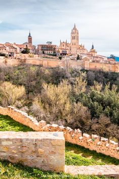 an old city is seen in the distance with trees and grass on the ground below