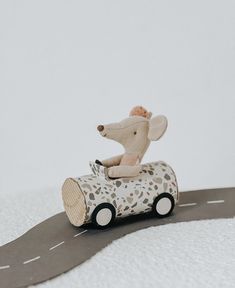 a toy mouse driving a car on a road