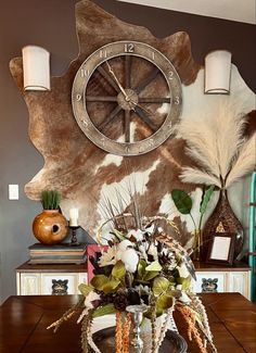 a vase filled with flowers sitting on top of a wooden table next to a clock