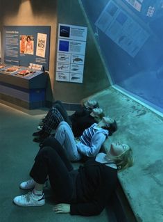 two people laying on the ground in front of an aquarium