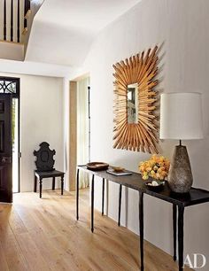 a living room with wood floors and a sunburst mirror on the wall above it