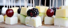 fruit and cheese skewers are arranged on a cutting board