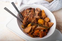 a bowl filled with meat and vegetables on top of a white plate next to a towel