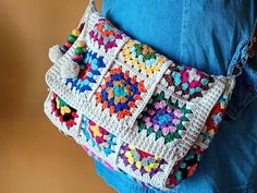 a crocheted purse is being held by a woman's back with blue jeans