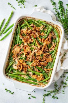 green bean casserole with chicken and parsley in a white dish on top of a napkin