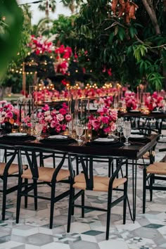 a table set up with pink flowers and candles for an outdoor wedding reception in the garden