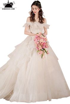 a woman in a white wedding dress holding a pink bouquet and posing for the camera