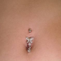 a close up of a woman's stomach with a butterfly belly ring on it