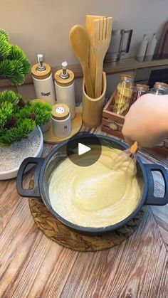 a person is cooking food in a pan on a table with plants and other kitchen items