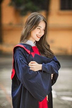 a woman in a graduation gown is posing for the camera with her arms folded over her chest