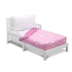 a small white bed with pink sheets and stars on the pillowcase is next to pillows