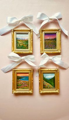 four framed pictures hanging on a wall with white ribbons tied around them and bows attached to the frames