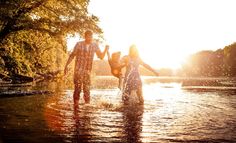 three people in the water with their arms around each other and one person holding hands