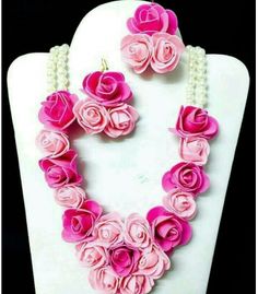 a necklace and earring set made out of pink flowers on a white mannequin