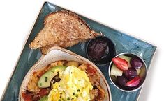 a blue plate topped with an egg and toast next to fruit on a white table