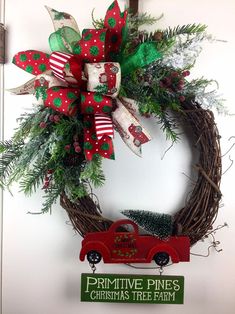 a christmas wreath with a red truck and green bow hanging on the front door,