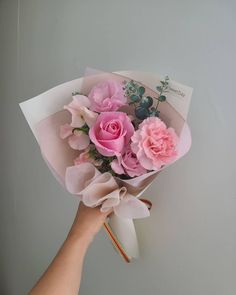 a hand holding a bouquet of pink roses