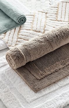 three towels folded on top of each other in front of a white and blue rug