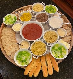 a platter filled with different types of pasta and dipping sauces on bread sticks