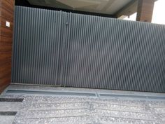 an open metal gate on the side of a building next to a wooden wall and steps