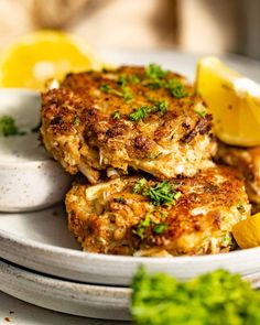 two crab cakes on a plate with lemon wedges