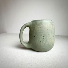 a green mug sitting on top of a white table