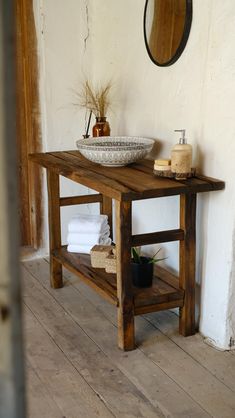 a wooden table with two bowls on top of it and towels stacked next to it