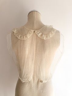 Mesh and lace delicate sheer sleeveless top. Super rare and special example of a Victorian era under garment, though today these are easy to wear on their own with fun bralettes for layering and jeans. Amazing wearable condition for age. The original price tag is still pinned in place. Snaps at top on back and open. Sweet little rounded lace embellished collar. Fabric: cotton Fit: SEra: 1910's Measurements: Bust 36" Shoulder 15.5" Length 18 (front), 14 (back)" Waist 29" Condition: Very good. Unw Vintage Sheer Tops For Wedding, Vintage Formal Lace Top With Lace Trim, Delicate Lace Tops For Daywear, Vintage Tops For Summer Weddings, Vintage Lace Top With Lace Collar For Summer, Vintage Lace Top For Summer Daywear, Vintage Sleeveless Wedding Tops, Vintage Delicate Lace Tops For Spring, Vintage White Tops For Layering