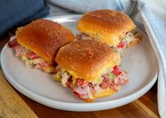 two sandwiches sitting on top of a white plate next to a blue towel and napkin