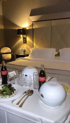 a bed room with a neatly made bed and two plates of food on the table