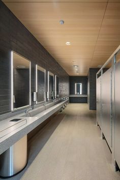 an empty public restroom with sinks and urinals on either side of the stalls