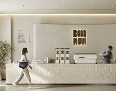 a woman walking past a counter in a restaurant with coffee machines on the wall behind her