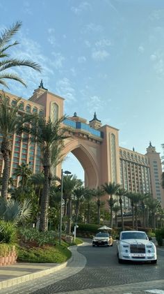 cars are driving down the street in front of an ornate building and palm trees on either side