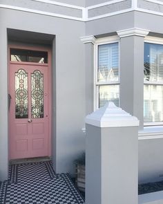 a pink front door on a grey house with black and white checkered flooring