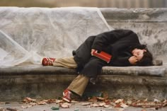 a person laying down on a bench with their head in his hands and eyes closed