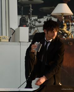 a man in a suit and tie sitting on top of a table next to a microphone