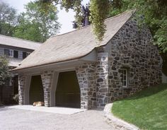 a stone building with two garages and a dog laying in the driveway