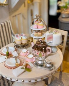 a table topped with cakes and cupcakes on top of white plates next to a chair