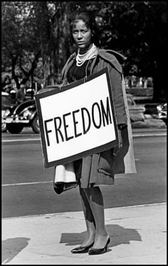 a black and white photo of a woman holding a sign that says, freedom