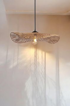 a light fixture hanging from the ceiling in a room with white walls and shadows on the wall