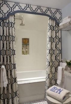 a bath room with a toilet a tub and a shower curtain next to a window