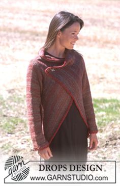 a woman standing in the grass wearing a brown and red sweater with an open neck