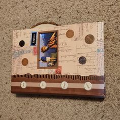 an altered photo frame with buttons and writing on the bottom is sitting on carpeted floor