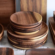 a stack of wooden plates sitting on top of a table next to other wood dishes