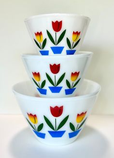 three bowls are stacked on top of each other with tulips painted on them