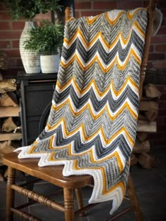 a chair with a blanket on top of it next to a brick wall and potted plant