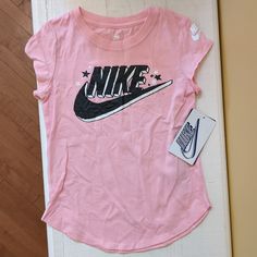 Nike Girl's Top. Light Pink With "Nike" Across The Front. Brand New With Tags! Pink Graphic Print T-shirt For Playwear, Pink Graphic T-shirt For Playwear, Playful Pink Tops With Letter Print, Pink Letter Print Tops For Playwear, Pink Short Sleeve Tops For Playwear, Pink Tops For Playwear In Spring, Sporty Pink Top For Playwear, Sporty Pink Tops For Playwear, Pink T-shirt For Playwear In Spring