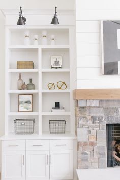 a living room filled with lots of white shelves and furniture next to a fire place