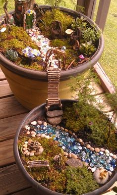 two potted plants that are sitting on a deck with rocks and gravel in them